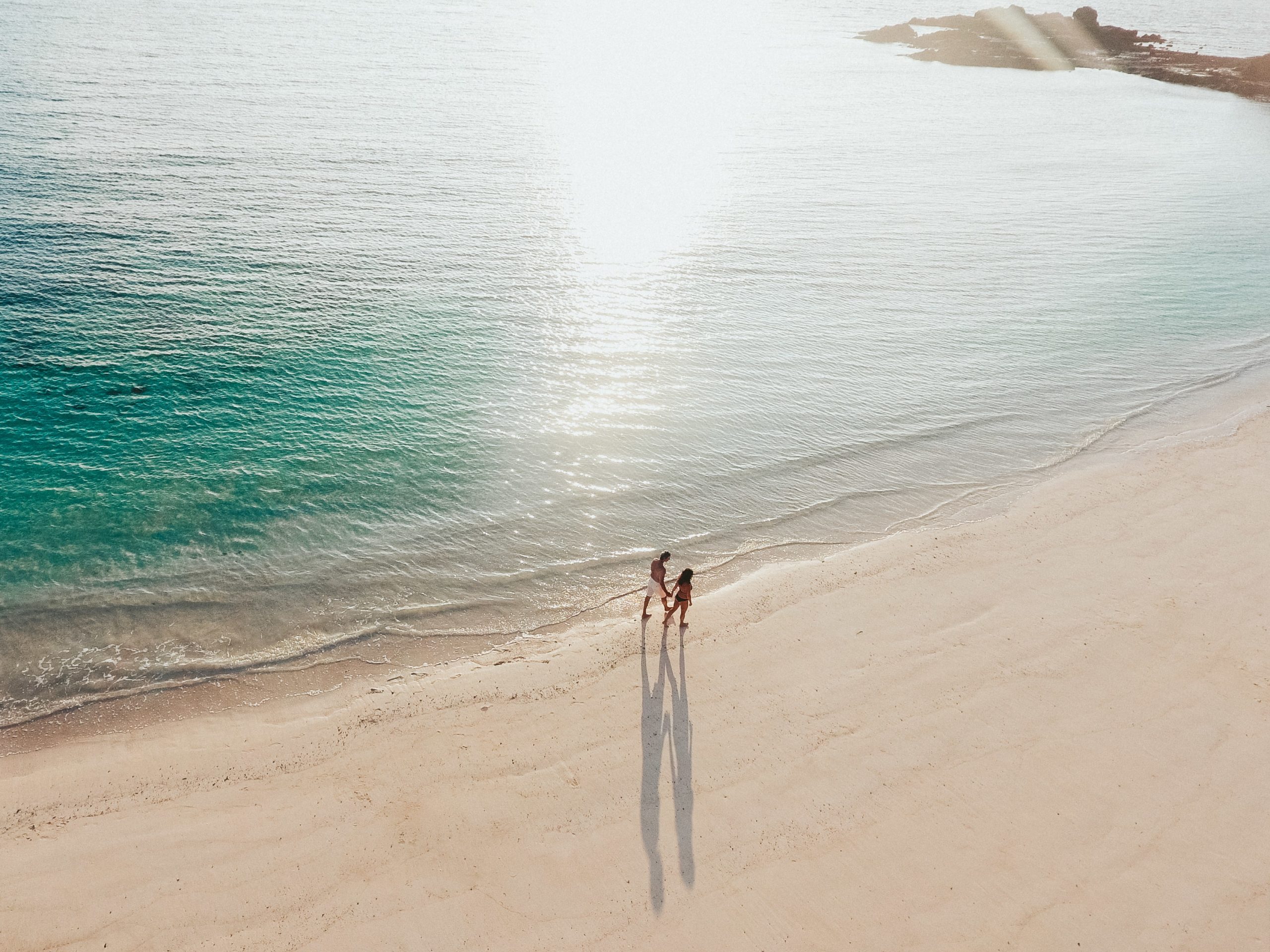 Couple walking along a white sand beach in Fiji at sunset