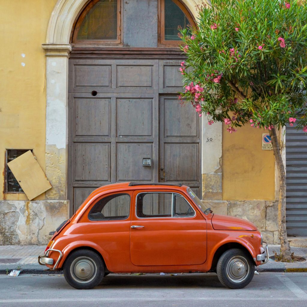 Orange vintage car parked on the street in Sicily 
