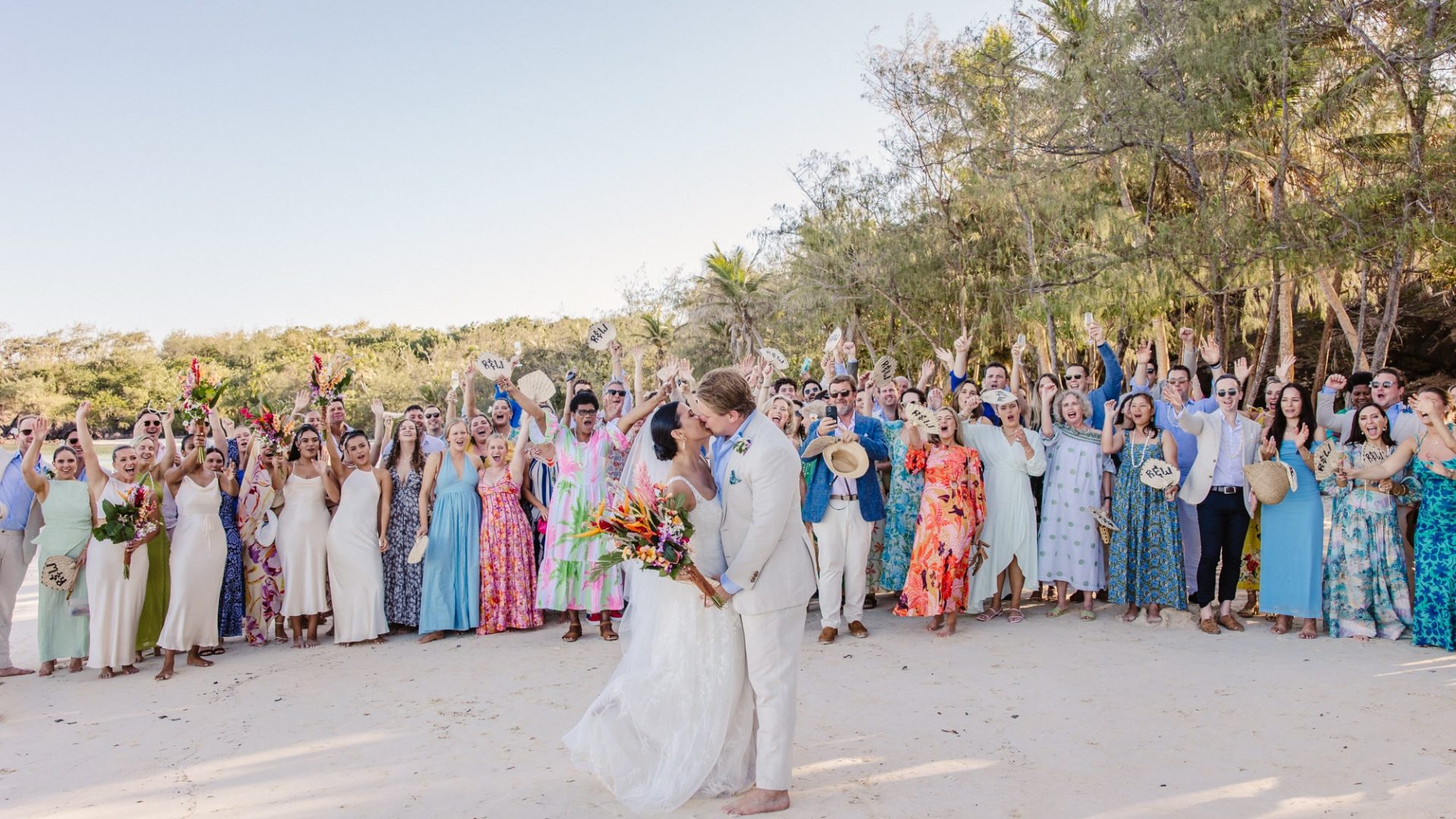 A romantic beach wedding ceremony in Fiji with a couple exchanging vows by the ocean, surrounded by tropical scenery and celebrating with family and loved ones.
